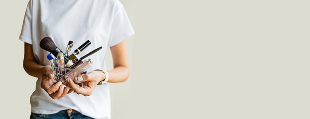 Young woman hands holding trolley with makeup products and gadgets. Female vanity and shopping addiction. Horizontal web banner with copy space. Mockup, template © Алина Бузунова