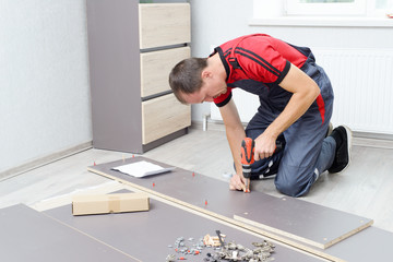 Close-up of the process of installation a furniture. Man's hands working with a screwdriver.