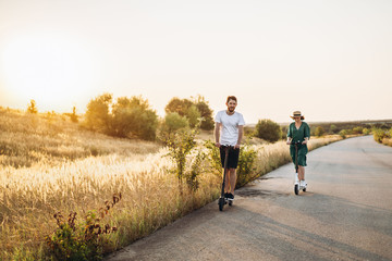 Fototapeta premium Young couple on vacation having fun driving electric scooter on the road in the countryside. Content technologies. Copy space