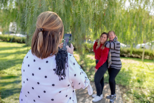 girl taking pictures of two girls in the outdoor park, lifestyle concept
