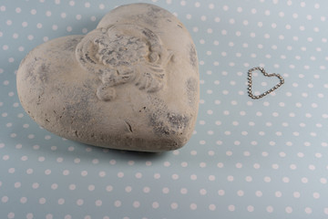 White stone heart and sparkling crystal chain heart on white dotted light blue background.