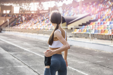 Morning exercises on stadium. Young, sporty and slim woman making exercises