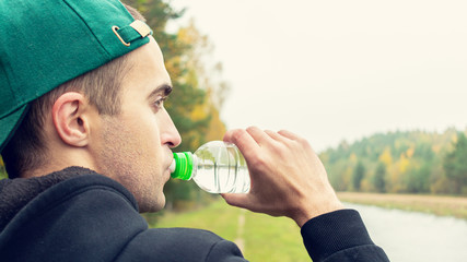 Concept of sports, training and active lifestyle. Young man quenches his thirst after a difficult...