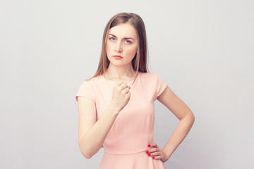 Angry woman threatening the first, grey background, portrait, toned