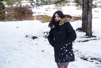 Young happy and beautiful teenage girl dressed in winter clothing standing at snow and smiling.