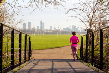 Woman jogging in Hackney Marshes in London, UK