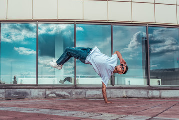 man in flight, standing on one arm, young guy dancer, summer city, dancing street dances, modern...
