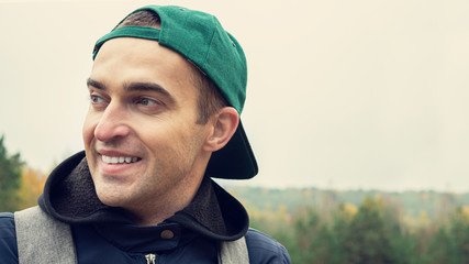 Portrait of young attractive man smiles outdoor, closeup, copy space, 16:9