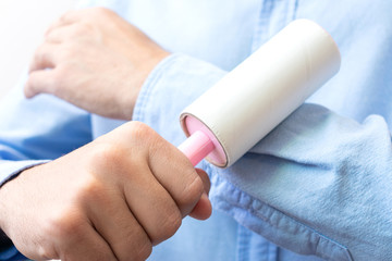 Man cleaning the shirt with adhesive sticky roller, close up