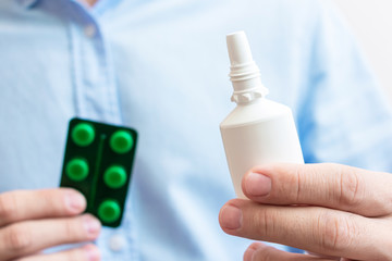 Men's hands with medicine nose spray and pill pack, close-up