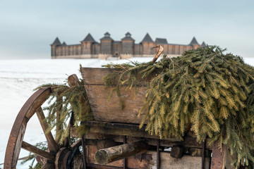 Obraz premium Wooden cart on springs in the yard on a winter cloudy day. The cart is loaded with hay covered with a thin layer of snow.
