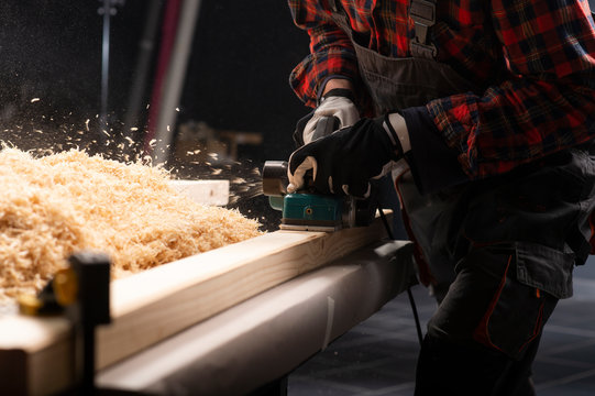 Carpenter works with electrical planer