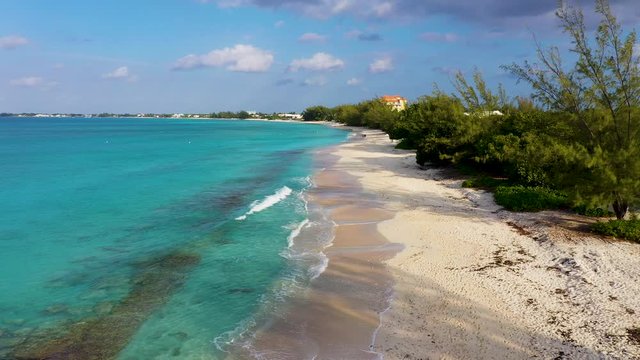 aerial drone footage of seven mile beach, west bay and george town on the island of grand cayman in the cayman islands in the clear blue and green tropical waters of the caribbean sea