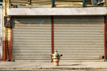 shop exterior with closed shutters, street facing store, sidewalk and hydrant