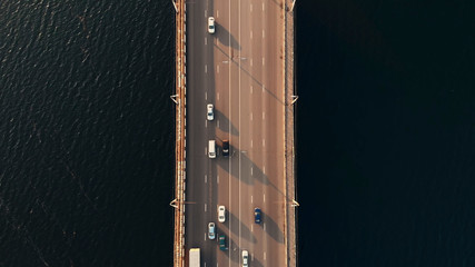 Top down aerial view of car traffic on bridge over river, drone shot. © DedMityay