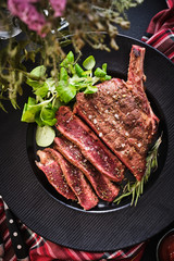 Steak on the bone. Rib eye. Tomahawk steak on the black plate with rosemary. Roasting - Rare. Entrecote
