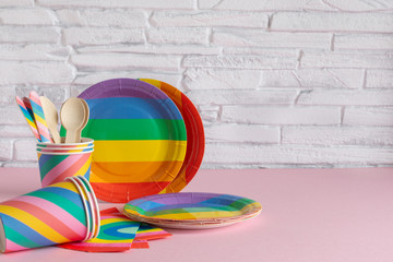 Rainbow colored disposable eco tableware on pink color background. Birthday party accessories,picnic utensil concept.