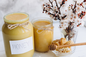 Spring composition, fresh honey with honeycomb, blooming cherry on a flat lay background