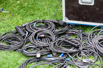Many coiled black electric wires at grass