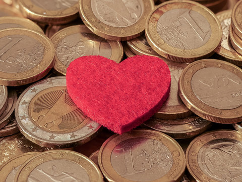 Close-up image of one and two Euro coins with red heart showing passion for money