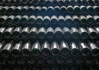 Dusty old wine bottles stacked together in a wine cellar