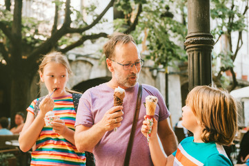 Happy father with children eating ice cream outdoors, family time, travel with kids