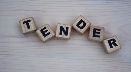 concept word tender on wooden cubes on a gray background