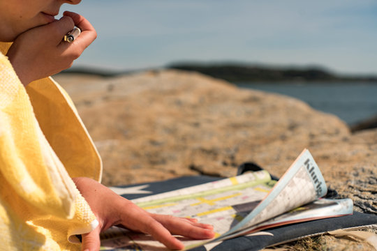 Woman Relaxing on beach Solving Crosswords during vacation on a sunny summer day. Vacation, Concept of leisure activities and Vacation chores.