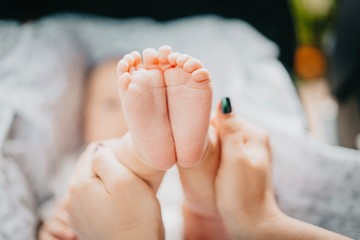 Naklejka premium Mother holding little baby boy feet in hands. Newborn concept