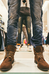 legs of mannequins in the store dressed in blue jeans and brown leather shoes