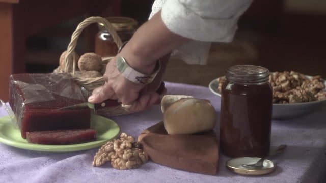 Hand slicing artisan quince paste served with walnuts, bread and jam