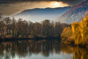 Trees at the river bank. Morning panorama of the river Mur in Europe Styria. Autumn - winter landscape.