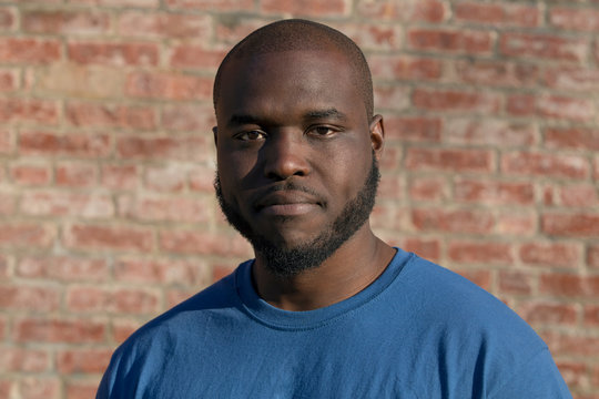 african american male construction worker in plain t-shirt millennial on brick wall 