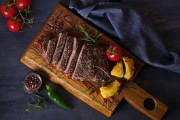 Beef steak fillet with roasted potatoes, rosemary and tomatoes. Overhead horizontal image