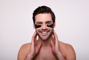 Smiling happy man with black patches on his face.