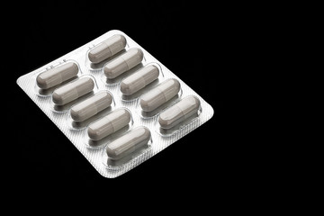 Medicine. White capsule pills in blister packs on a black background. Healthcare concept. Antibiotics and antimicrobial capsule tablets. Pharmaceutical industry.