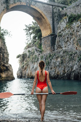 Fototapeta na wymiar beautiful girl in a red swimsuit on the beach with a paddle