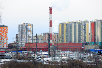 Obraz premium Panorama of the city with multi-storey residential buildings, a motorway, a power station and power lines, in winter
