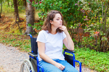Young happy handicap woman in wheelchair on road in hospital park waiting for patient services....