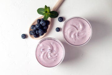 two fresh blueberry yogurt with blueberries on a white texture table, top view