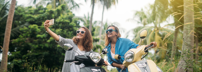 A pair of beautiful women travel by scooter through the jungle in Southeast Asia. Selfies © Anna
