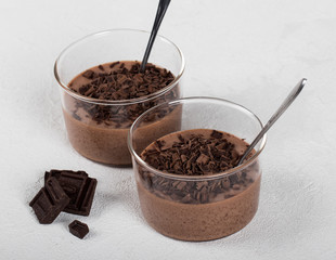 Italian dessert chocolate Panna cotta with chocolate pieces in a glass Cup on a light background