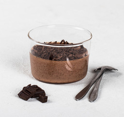 Italian dessert chocolate Panna cotta with chocolate pieces in a glass Cup on a light background