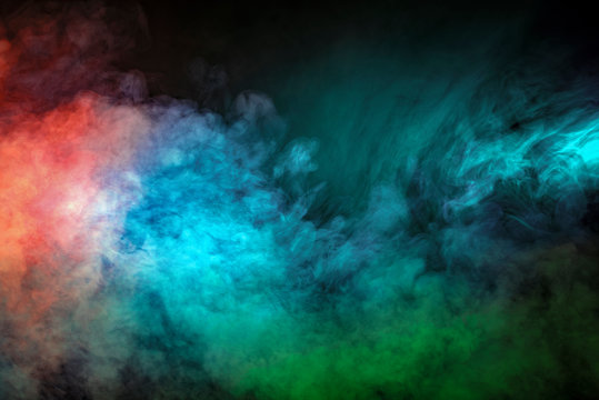 Abstract backlit smoke texture in red blue green on black background.