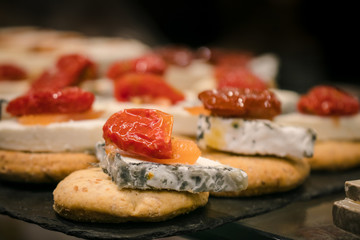 Naklejka premium Blue cheese with dry tomato pintxos or tapas, spanish canapes, in San Miguel Market Madrid 