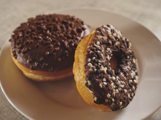 Two taste chocolate round doughnut on a white plate. Bakery product. Selective focus.