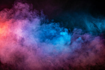 Backlit smoke abstract texture in pink blue red on black background.