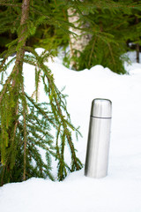 a thermos of hot tea in the forest, in the open air.