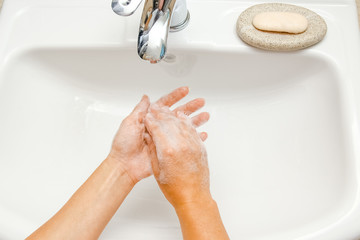 a Washing hands with soap under the faucet with water