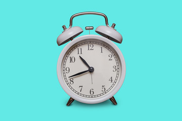Old fashioned white alarm clock on aquamarine background